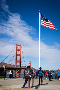 People on suspension bridge against sky