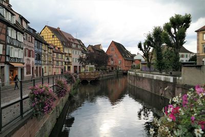 Buildings by river against sky