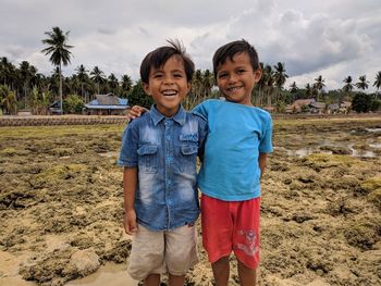 Portrait of smiling brothers standing at beach