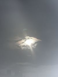 Low angle view of sun shining through clouds