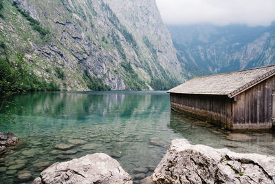 Boathouse by lake against mountains