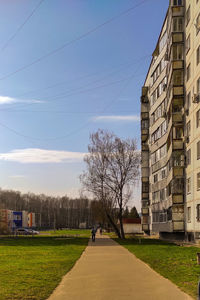 Road amidst trees and buildings against sky