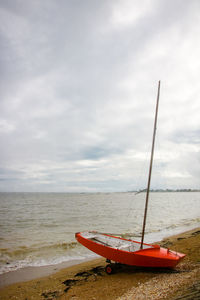 Sailboat moored on beach against sky