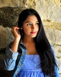 Portrait of beautiful young woman standing against wall