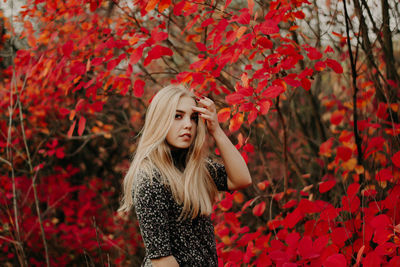 Full length of young woman standing on red autumn leaves