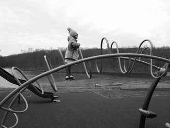 Side view of girl standing on metal against sky