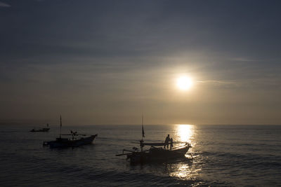 Silhouette boat sailing on sea against sky during sunset