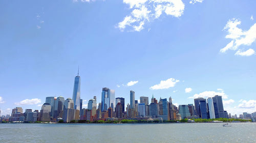 Sea by modern buildings against sky in city