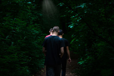 Rear view of man and woman walking in forest