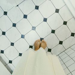 Low section of man standing on tiled floor