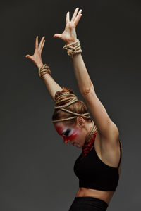 Portrait of young woman gesturing against black background