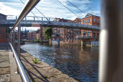 Bridge over river in city against sky