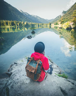 Rear view of man looking at lake against mountain