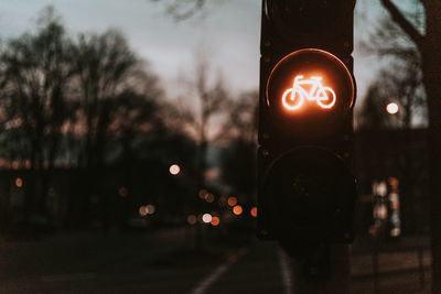 Illuminated bicycle lane sign on stoplight in city at dusk