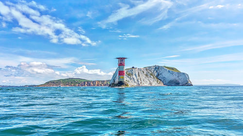 Lighthouse by sea against sky