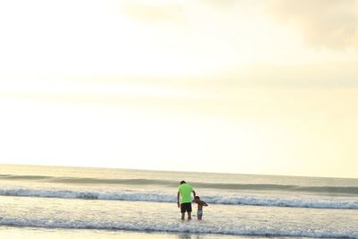 Rear view of men on beach against sky