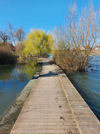 Footpath by lake against clear sky