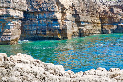 Rocks by sea against blue sky