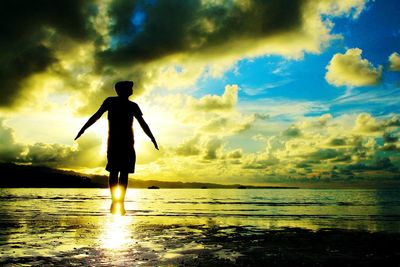 Silhouette of people standing on beach at sunset