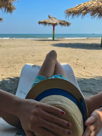 Midsection of woman relaxing on sand at beach