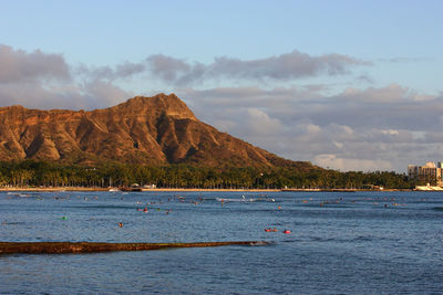 Scenic view of sea by mountains against sky