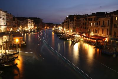 Canal amidst illuminated buildings in city at night