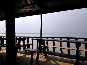 Empty chairs and table by sea against clear sky