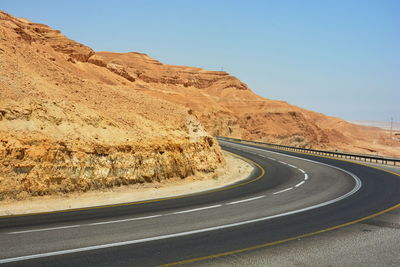 Scenic view of road by mountain against clear sky