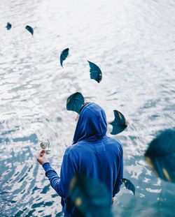 High angle view of leaves flying over man standing at lakeshore