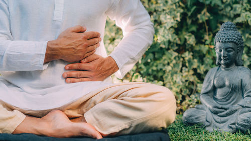 Male therapist performing reiki therapy self-treatment holding hands over his stomach. 