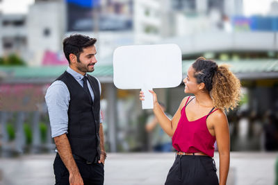 Young man holding woman standing on mobile phone