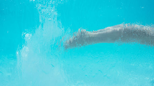 Low section of man swimming in pool