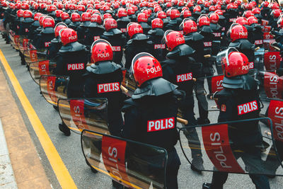 Rear view of police force marching on road in city