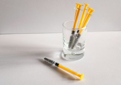 Yellow syringe in glass on white background