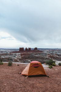 Orange tent held down by rocks at campsite in the maze utah