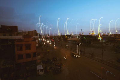 Cars on illuminated city against sky at night