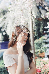 Young woman with eyes closed standing by plants in park