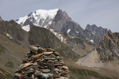 Stack of rocks on snowcapped mountains against sky
