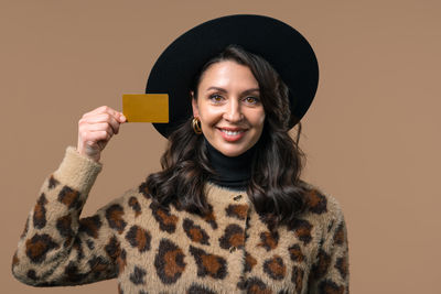 Portrait of young woman holding gift against yellow background