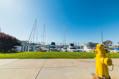 Sailboats at harbor against clear blue sky