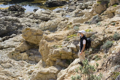 Man hiking while looking through binoculars at french riviera