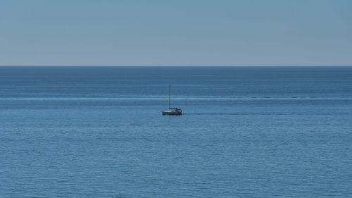 Sailboat sailing on sea against clear sky