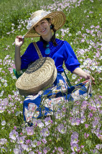 Woman wearing hat while standing by plants on field