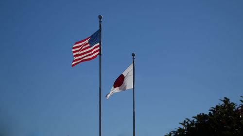 Low angle view of flags flag against clear blue sky