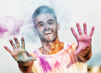 Cheerful man playing holi against sky