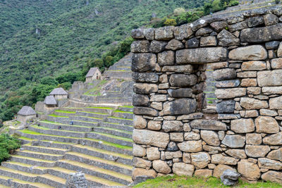 Stone wall and window overlooking inca terraces and huts at machu picchu, peru