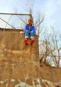 Girl playing on fence against sky