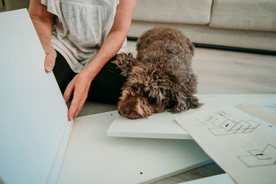 Midsection of woman with dog working on wood on table