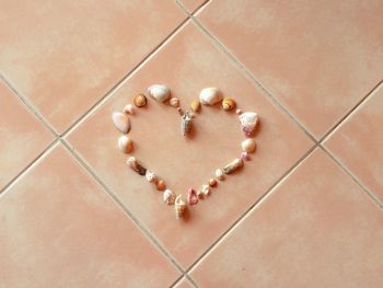 High angle view of heart shape made by seashells on tiled floor