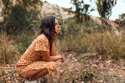 Side view of young woman sitting on land